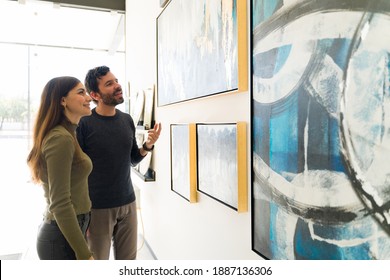 Good-looking Young Woman And Man Are Talking About Art While Visiting A Painting Exhibition At The Art Gallery