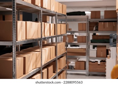 Goods packages lying on storehouse racks, waiting for transportration in empty storage. Products cardboard boxes on high shelves in shop distribution department warehouse