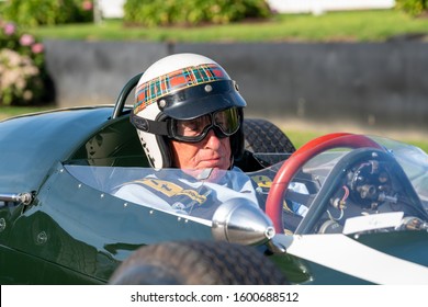 Goodwood, Sussex / UK - 14 Sept 2019: Sir Jackie Stewart, wearing his trademark tartan and white helmet, sits behind the red steering wheel of a classic race car at the annual vintage Revival event.
