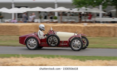 Goodwood, Sussex / UK - 5th July 2019: Vintage Bugatti Motor Car Speeds Past Spectators In The Historic Festival Of Speed Hill Climb.  The Driver Sits High At The Wheel Of The Cream / Maroon Vehicle.