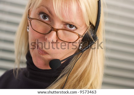 Goofy businesswoman makes a face while she talks on her phone headset.