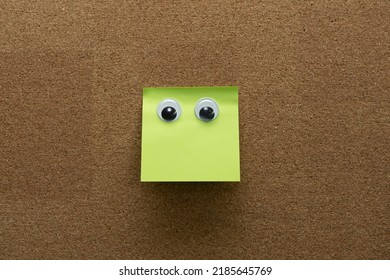 googly eyes on green clean  sticky note on cork board concept using sticky notes 