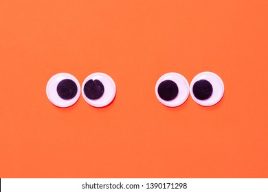 Googly eyes: One pair strabismus and squint mad googly eyes and one pair normal funny eyes next to each other on a orange background. - Shutterstock ID 1390171298