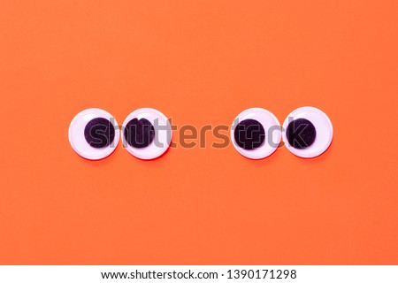 Googly eyes: One pair strabismus and squint mad googly eyes and one pair normal funny eyes next to each other on a orange background.