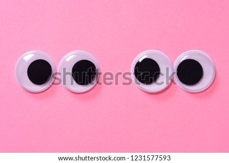 Googly eyes of pair of lovers on rose background. Close up.