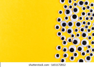 Googly plastic eyes pattern on yellow backgroud. Used for imitation of eyeballs for handcraft toys and dolls and others creativity. Flat lay.