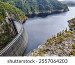 Gordon Dam in Tasmania, an impressive concrete structure surrounded by rugged cliffs and a lake in a remote wilderness