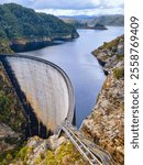 Gordon Dam in Tasmania, an impressive concrete structure surrounded by rugged cliffs and a lake in a remote wilderness