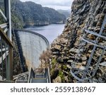 Gordon Dam in Tasmania, an impressive concrete structure surrounded by rugged cliffs and a lake in a remote wilderness