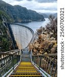 Gordon Dam in Tasmania, an impressive concrete structure surrounded by rugged cliffs and a lake in a remote wilderness