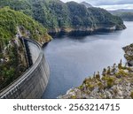 Gordon Dam in Tasmania, an impressive concrete structure surrounded by rugged cliffs and a lake in a remote wilderness