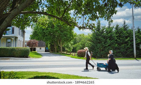 Gordonville, Pennsylvania, June 2020 -An Amish Family Walking Along A Country Road Pulling A Wagon With A Small Child In It