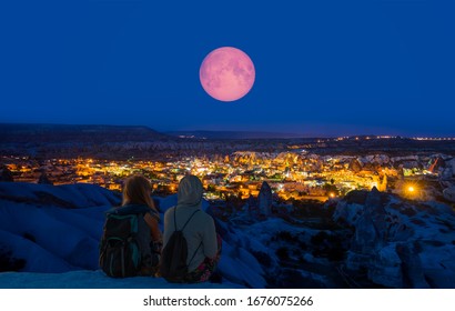 Goreme village in Cappadocia at twilight blue hour - Girls watching full moon at the hill of Cappadocia  "Elements of this image furnished by NASA "  - Powered by Shutterstock