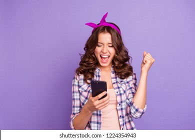 Gorgeous adorable good-looking leisure lifestyle lady in casual style stylish trendy checkered shirt with open mouth her curly brunette hairstyle she isolated on purple background raised fist up
