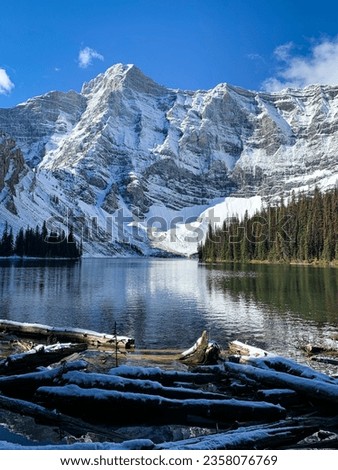 Gorgeous alpine lake after a fresh snowfall. Backdropped by an imposing snow covered mountain. 