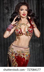 Gorgeous arabian woman bellydancer dancing in traditional bellydance costume over black studio background. Sexy turkish belly dancer posing in bridal baladi dress with jewelry. 