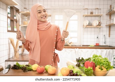 Gorgeous Asian woman prepare the vegetables to cut for salad. Muslim woman cooking amazing salad breakfast. Fresh ingredients on her table. - Powered by Shutterstock