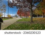 a gorgeous autumn landscape at Nashville Public Square Park with green and red trees, fallen autumn leaves, grass, a footpath and buildings in Nashville Tennessee USA