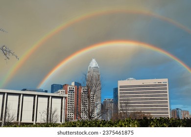 a gorgeous autumn landscape with skyscrapers and office buildings in the city skyline with blue sky clouds and a rainbow at Marshall Park in downtown Charlotte North Carolina USA