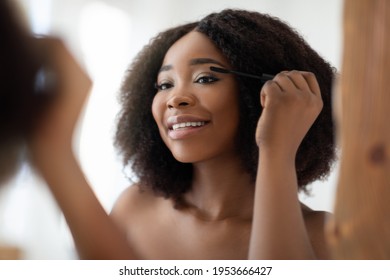 Gorgeous Black Woman Applying Mascara On Her Lashes In Front Of Mirror At Home. Attractive African American Lady Using Decorative Cosmetics, Making Her Daily Routine, Pampering Herself