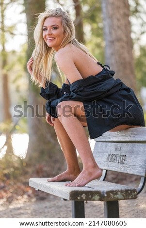 A gorgeous blonde bikini model poses outdoors near a lake while enjoying the summer weather.