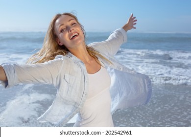 Gorgeous blonde spreading arms out at the beach on a sunny day - Powered by Shutterstock