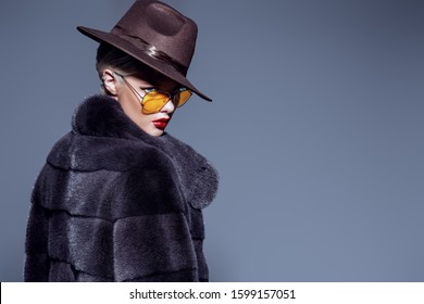 Gorgeous blonde woman posing in luxurious fur coat and a hat. Fashion, beauty. Studio shot.