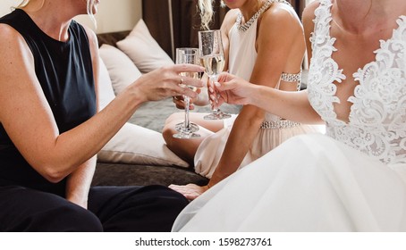 Gorgeous Bride And Bridesmaids Toasting Champagne And Having Fun On Wedding Morning. Cheerful Young Girlfriends Raise A Toast And Clink Glasses. Bride Morning And Girlfriends. Film Noise