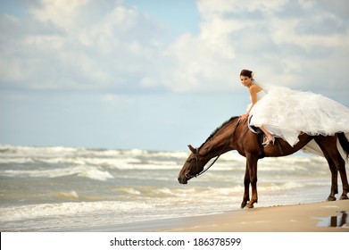 Gorgeous bride on a horse on sandy beach by the sea.