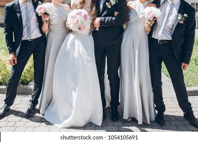 gorgeous bride with peony bouquet and stylish groom posing in sunny garden with bridesmaids and groomsmen on wedding day. luxury wedding couple having fun with friends - Powered by Shutterstock