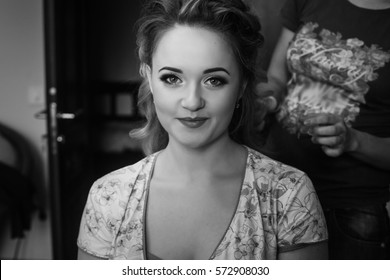 Gorgeous Bride Smiling While Getting Her Hair Done By Professional Stylist. Getting Ready For Wedding Ceremony In Room In The Morning. Happy Stylish Woman. Black White Photo