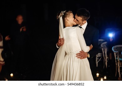 Gorgeous Bride And Stylish Groom Having Their First Kiss  At Romantic Candle Light At Evening Wedding Ceremony