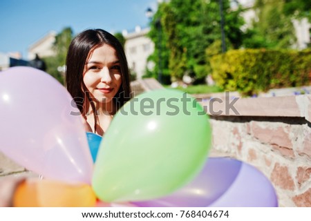 Gorgeous brunette girl at street of city with balloons at hands.