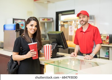 Gorgeous Brunette Holding A Bag Of Popcorn And A Soda Next To A Concession Stand In A Movie Theater