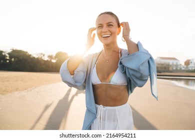 Gorgeous Caucasian woman enjoying vacations while walking on the beach feeling calm and carefree. Happy and Beautiful healthy female in white summer cloth strolls on seashore during holidays travel - Powered by Shutterstock