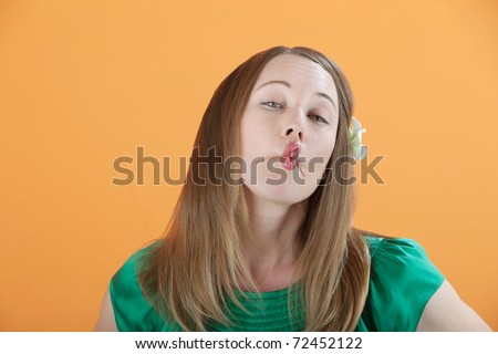 Gorgeous Caucasian woman pretends to be kissing isolated on an orange background