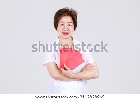 Gorgeous Chinese senior woman happy to propose sale promotion and offer red envelope of new year cash gift as advertisement for customer to enjoy benefit of lucky shopping for celebration on holiday.