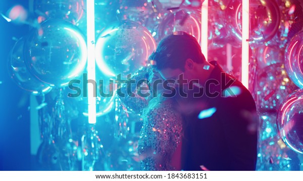 Gorgeous couple dancing with passion in
nightclub. Sweet girl and guy moving in dance at night club party.
Young people clubbing on neon lamps
background.