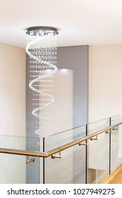 A Gorgeous And Elegant Chandelier Hands Above A Staircase In A Modern Home Setting.