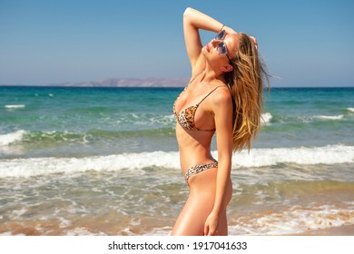 Gorgeous fashion model posing on a sand beach. Summer holiday concept.