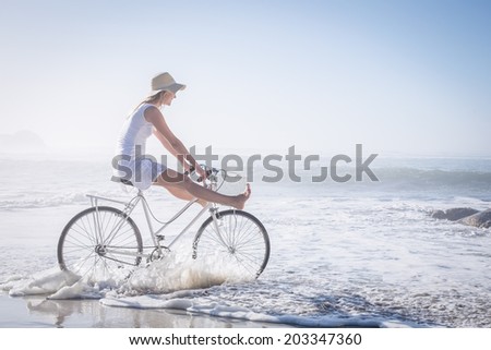 Gorgeous happy blonde on a bike ride at the beach on a sunny day