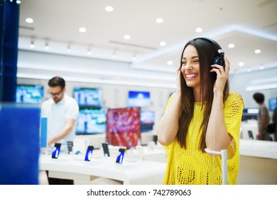 Gorgeous Happy Girl Testing Headphones In A Tech Store.