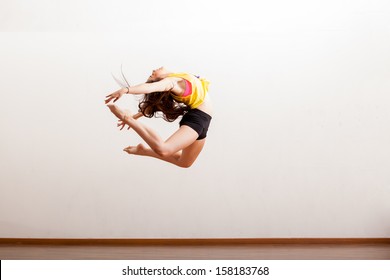 Gorgeous Jazz Dancer In The Middle Of A Jump During A Dance Performance In A Studio