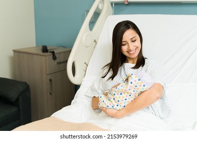 Gorgeous Latin Woman Looking At Her Adorable Newborn Baby After Giving Birth At The Hospital