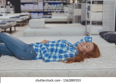 Gorgeous Long Haired Woman Lying On A New Orthopedic Bed At Furniture Store, Copy Space. Attractive Female Cusotmer Trying Comfortable Mattress On Sale At Furnishings Shop