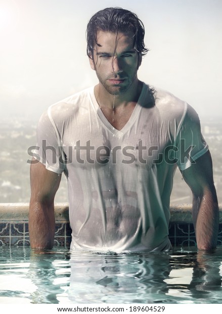 都会の背景に豪華なプールに立つ 濡れたぬれたtシャツの豪華な男性モデル の写真素材 今すぐ編集