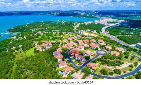 Gorgeous mansion homes in hilltop overlook neighborhood in suburb near Travis Lake near Austin Texas USA aerial drone view of Texas hill country colorful houses and lake in background