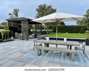 Gorgeous outdoor living backyard patio with pergola, outdoor rug,  tequila bar, dining set, couch, television, pool with waterfall , fire pit and stunning Techo Bloc patio pavers - Inspired by tulum.