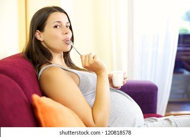 Gorgeous pregnant woman eating happy yogurt