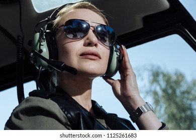 Gorgeous Professional. The Close Up Of A Pretty Young Female Helicopter Pilot Sitting Listening To Air Traffic Controller In Her Headphones And Being Ready To Start A Flight